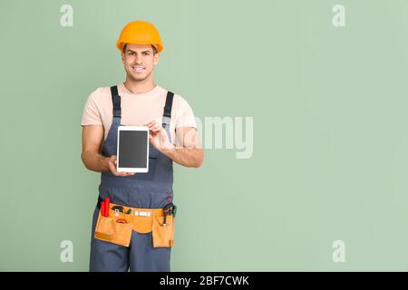 Handsome male worker with tablet computer on color background Stock Photo