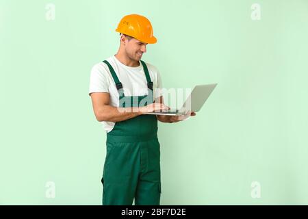 Handsome male worker with laptop on color background Stock Photo
