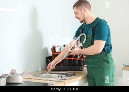 Handsome plumber repairing sink in kitchen Stock Photo