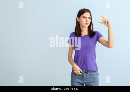 Troubled woman with menstrual tampon on light background Stock Photo