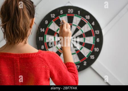 Young woman playing darts indoors Stock Photo