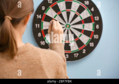 Young woman playing darts indoors Stock Photo