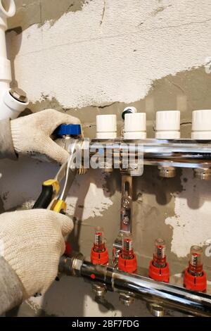 Installation of heating a new home, the worker connects the pipe to the heating of the collector.2020 Stock Photo