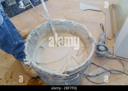 Construction worker mixing tile adhesive or cement with a power drill Stock Photo