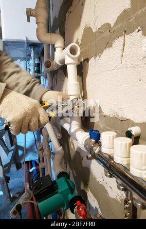 Installation of heating a new home, the worker connects the pipe to the heating of the collector.2020 Stock Photo