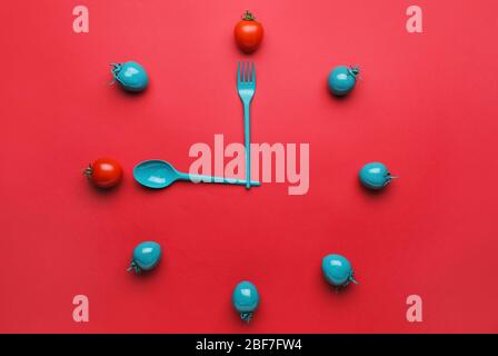 Creative clock made of tomatoes and cutlery on color background Stock Photo