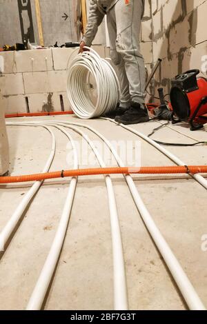 Installation of tubes on the floor to heat it, bringing the tubes to the collector.2020 Stock Photo