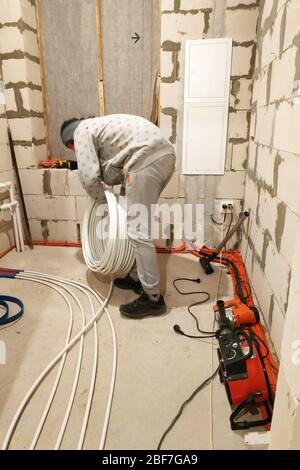 Installation of tubes on the floor to heat it, bringing the tubes to the collector.2020 Stock Photo