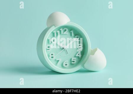 Alarm clock with broken egg shell on color background Stock Photo