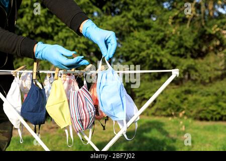 Drying mask hanging under the sun after use for disinfecting. Hygienic mask hanging on the rack outdoor after being washed for cleanness and hygiene d Stock Photo
