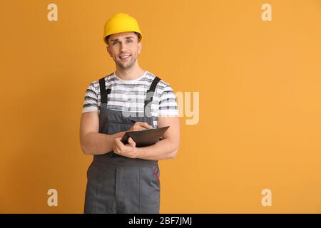 Handsome male worker with clipboard on color background Stock Photo