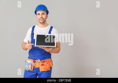 Handsome male worker with laptop on grey background Stock Photo