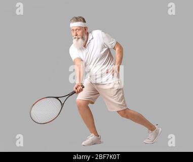 Sporty elderly tennis player on grey background Stock Photo