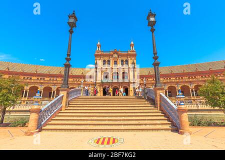 Seville, Andalusia, Spain - April 18, 2016: tourists on Leon Bridge with azulejos decorations in Spanish Square or Plaza de Espana across canal with Stock Photo