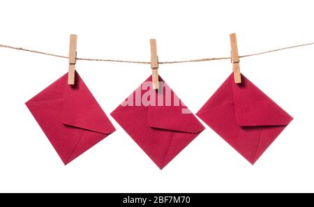 Paper envelopes hanging on rope against white background Stock Photo