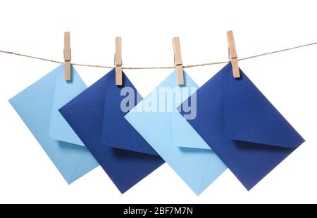 Paper envelopes hanging on rope against white background Stock Photo
