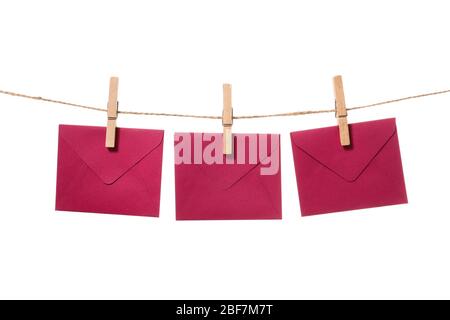 Paper envelopes hanging on rope against white background Stock Photo