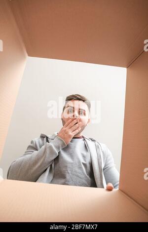 Shocked man with open box, view from inside Stock Photo