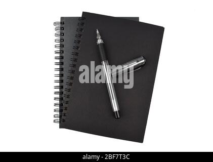 Couple of black colored note book diary and one black colored ball point pen placed together on a white background Stock Photo