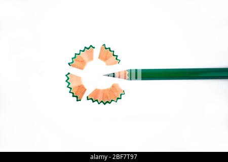 Green colored wood pencil crayon and some pencil shavings arranged as a circle on a white background Stock Photo