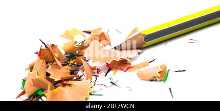 Yellow and silver color striped pencil crayons and some pencil shavings across a white isolated background Stock Photo