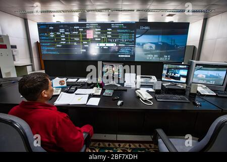 Oil refinery plant. Operational control center (control room). Operator in red work wear monitoring process. CNPC company. Stock Photo