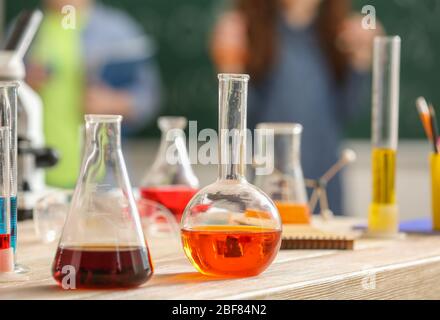 Laboratory glassware with liquids on table in classroom Stock Photo