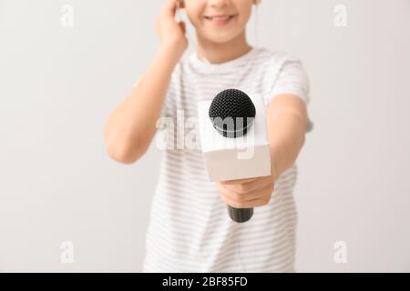 Little journalist with microphone on white background Stock Photo