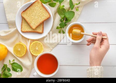 Woman drinking tea with honey at table, top view Stock Photo