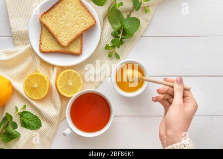Woman drinking tea with honey at table, top view Stock Photo