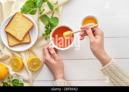 Woman drinking tea with honey at table, top view Stock Photo