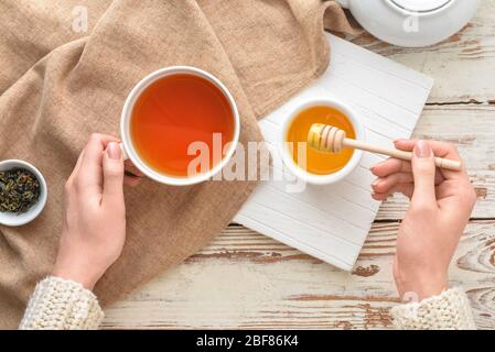 Woman drinking tea with honey at table, top view Stock Photo