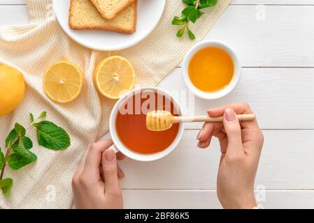 Woman drinking tea with honey at table, top view Stock Photo