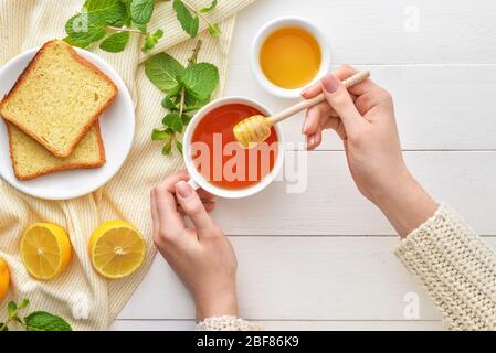 Woman drinking tea with honey at table, top view Stock Photo