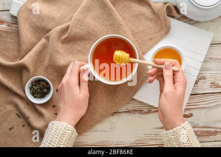 Woman drinking tea with honey at table, top view Stock Photo