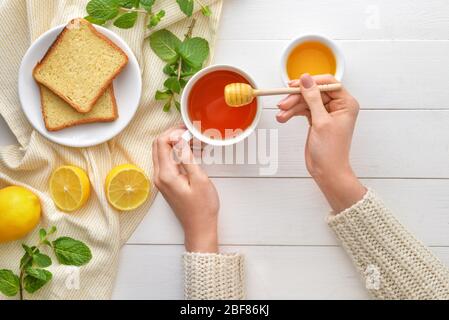 Woman drinking tea with honey at table, top view Stock Photo