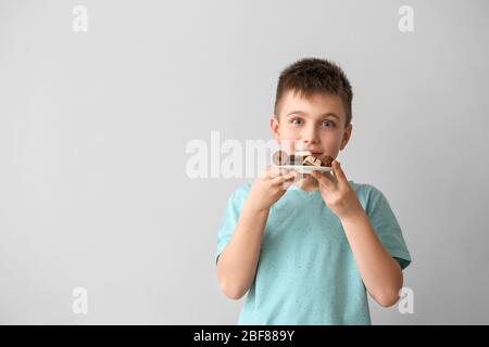 Cute little boy with chocolate candies on light background Stock Photo