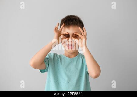 Funny little boy with chocolate candies on light background Stock Photo