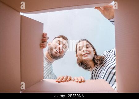 Young couple looking inside cardboard box, bottom view Stock Photo
