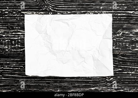Crumpled white paper on a black wooden table. Abstract background for design. Art stylized baner or mock up with copy space for a text. Stock Photo