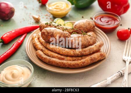 Plate with tasty grilled sausages and sauces on color background Stock Photo