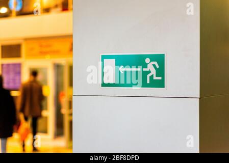 Emergency exit sign on wall in public place. Stock Photo