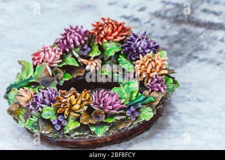 yellow red cemetery flowers in graveyard on headstone. Artificial funeral flower wreath lying on the tombstone.  Death, loss, condolence concept. Stock Photo