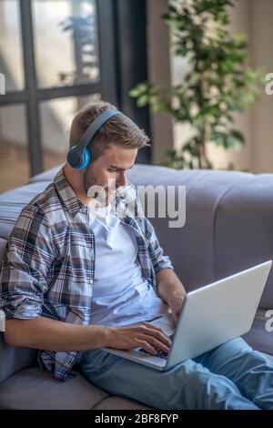 Young man in a checkered shirt writing an email Stock Photo