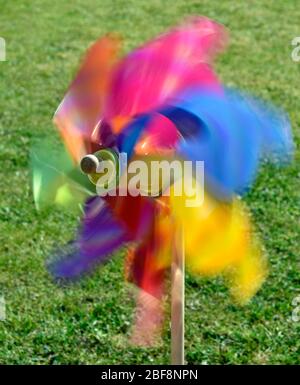 Colourful toy windmill against the sun and a blue sky. Stock Photo