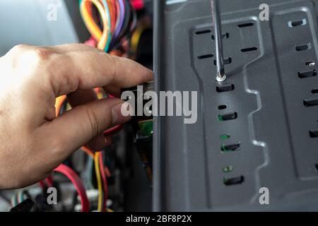 Hands of the technician repairing a computer. Hardware instalation. Turn-screw. Stock Photo