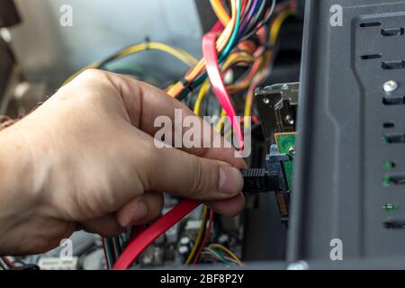 Hands of the technician repairing a computer. Hardware instalation. Turn-screw. Stock Photo