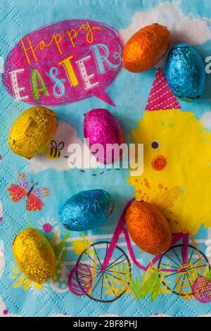 M&S choccy eggs, solid milk chocolate eggs on Happy Easter napkin serviette - foiled solid milk chocolate mini eggs Stock Photo