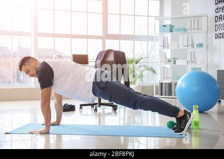 Man doing exercises in office Stock Photo