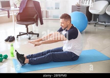 Man doing exercises in office Stock Photo